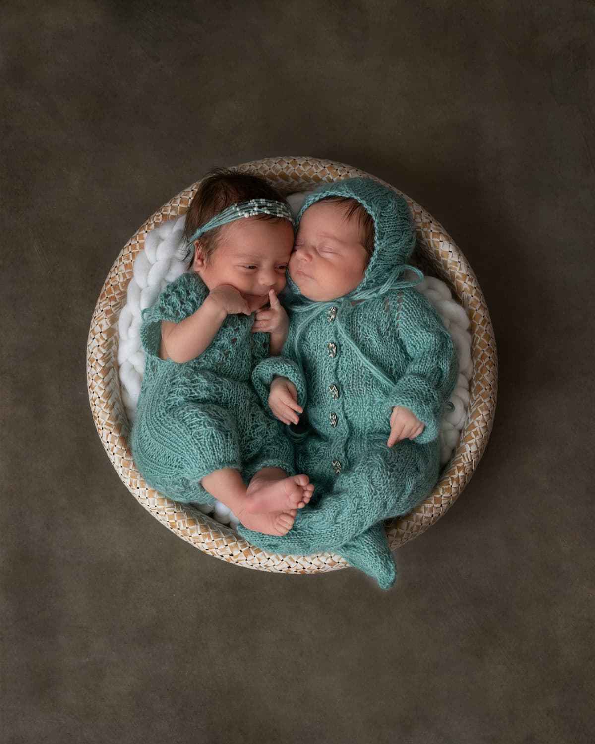Newborn twins in matching knitted outfits
