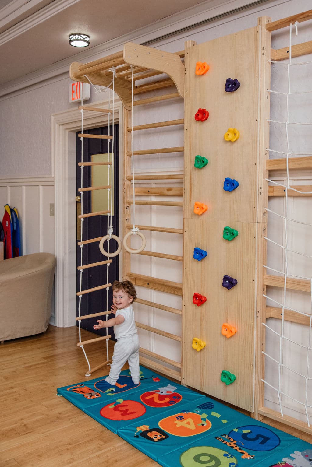Toddler exploring the climbing wall and rope ladder